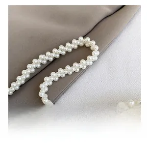 Close-up of elegant handmade woven white pearl handbag handle with high-gloss finish