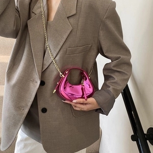 Mini sac demi-lune rose métallique avec bandoulière chaîne dorée porté par un mannequin