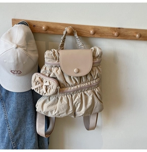 Detail of beige ruffled nylon backpack with cute bow coin purse on a wooden hook