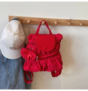 Detailed view of a red ruffled nylon backpack with a matching bow pouch on a hook
