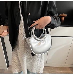 Silver metallic crescent bag with handle and crossbody strap shown on a model