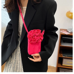 Detailansicht einer leuchtend rosa 3D-Rosen-Umhängetasche kombiniert mit schwarzem Outfit