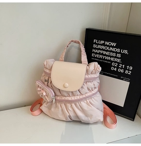 Detail of pink pleated nylon backpack with off-white flap and cute bow bag charm