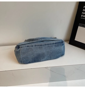Detail view of the washed denim fabric texture and reinforced stitching on the tote bag base