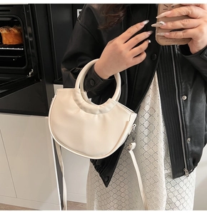 Detail of cream crescent bucket bag with thick round handle and detachable shoulder strap