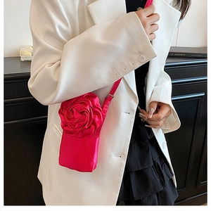 Detail einer leuchtend rosa 3D-Blumen-Stoff-Handytasche mit Satinstruktur und Gurt