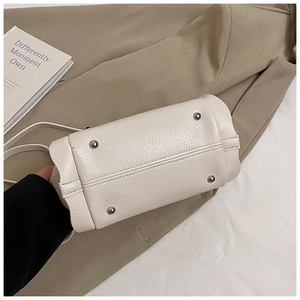 Detail shot of beige handbag base with four protective metal feet on lychee grain leather