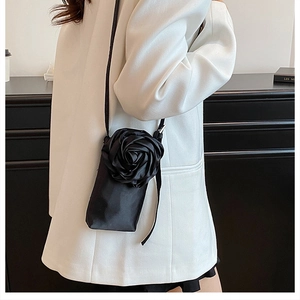 Detailansicht der schwarzen Stoff-Handytasche mit 3D-Satinrose auf weißem Blazer