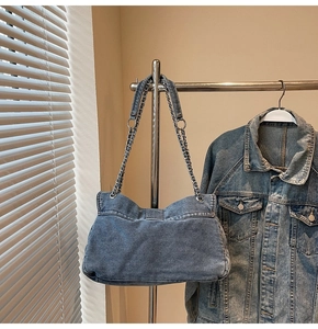 Detail view of denim tote bag hanging with silver chain strap and washed texture
