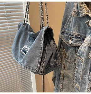 Detail of blue denim shoulder bag featuring silver chain strap and large square buckle