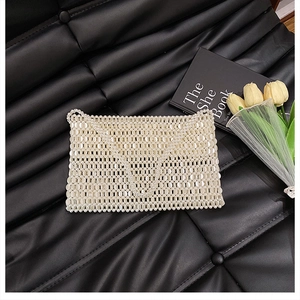 Close-up of a handmade white pearl beaded bag on a black quilted leather background