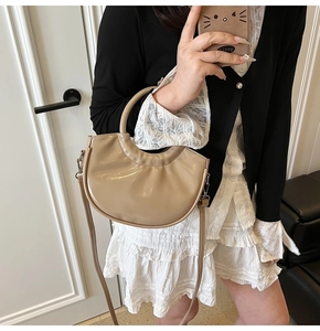Glossy beige crescent handbag with round handles and silver metallic side hooks
