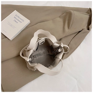 Top view of beige bucket bag showing interior lining and metal magnetic closure detail