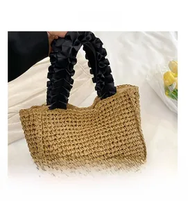 Detail shot of the hand-woven straw texture and black pleated fabric handle contrast