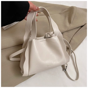 Detail of cream white pebbled leather bag featuring wavy handle and brand logo