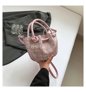 Close-up of woven leather bucket bag in soft pink with drawstring and knot details