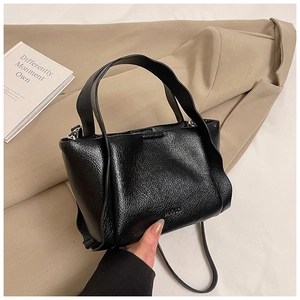 Detail of minimalist black lychee texture leather bucket bag on casual blazer