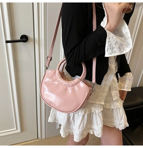 Detail of pink patent leather moon bag showing glossy texture and slim shoulder strap