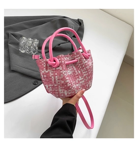 Detail of pink woven bucket bag with dual knot handles and detachable shoulder strap