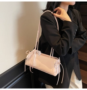 Detail of pink rectangular handbag with bow side ties and elegant white lace strap trim