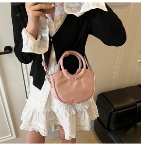 Detail showing meat pink half-moon handbag with a circular handle and adjustable strap