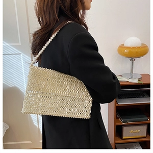 Close-up of elegant white pearl beaded handbag showing intricate weave and strap detail