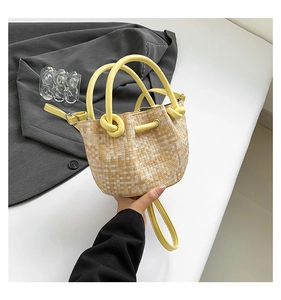 Detailed view of yellow woven bucket bag featuring round handle and drawstring closure