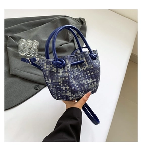 Detail of woven bucket bag featuring blue grey grid pattern and premium leather handles