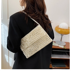 Close-up of handmade white pearl beaded shoulder bag on model with vintage interior