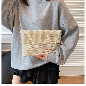 Detail of cream white handmade pearl beaded envelope clutch with elegant chain strap