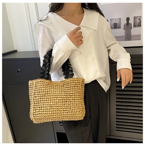 Detail of hand-woven straw tote bag with black ruffled handles for a summer beach look