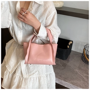 Detailed view of pink lychee leather handbag with side ruffle design and metal feet