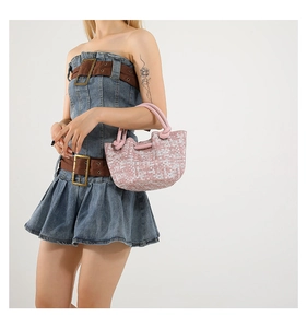 Close-up of pink woven texture tote bag with stylish knotted handle on denim dress