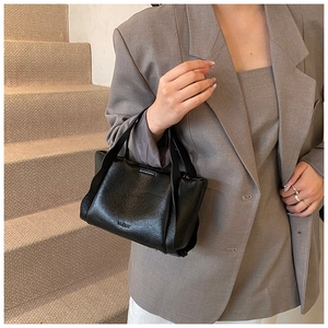 Close-up of black leather basket bag with lychee texture and embossed MURUA logo