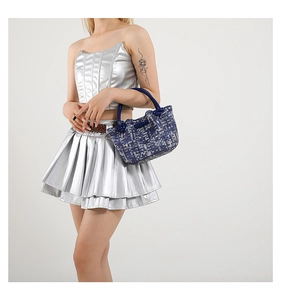 Detail of blue and white pixel woven handbag texture with navy handle shown on model