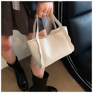 Detail of off-white lychee grain leather bucket bag with unique wavy edges and logo