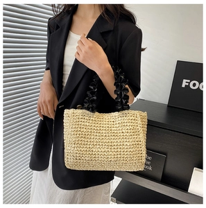 Detail of hand-woven beige straw tote with contrasting black ruched handle and texture