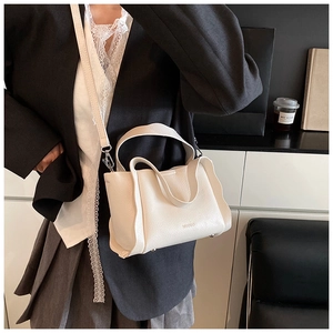 Detail of white lychee leather bucket bag with wavy sides and adjustable shoulder strap