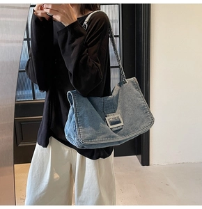 Detail view of the denim blue tote bag featuring silver metal buckle and chain strap