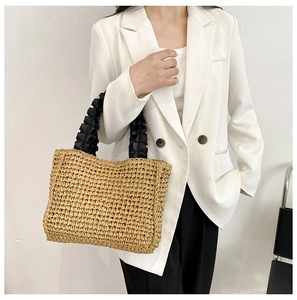 Detail of handmade straw tote featuring elegant black pleated satin cloud handles