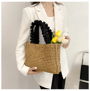 Handmade straw tote bag featuring decorative black ruffled handles and faux tulips inside