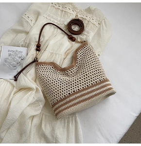 Detailed view of woven shoulder bag with wooden bead accent and leather strap