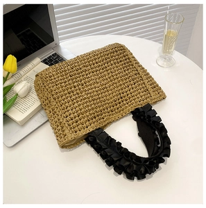 Detail of handmade straw tote bag with black ruffled handle and lifestyle background