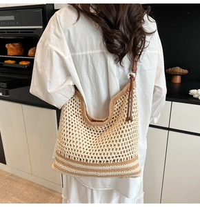 Detail of hand-woven hollow knit tote bag with brown leather strap and striped base