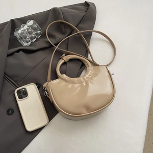 Beige crescent tote bag with round handle and detachable strap on aesthetic background