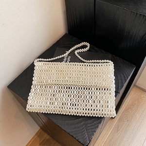 Handmade ivory pearl beaded handbag with strap for women on a dark wooden stand