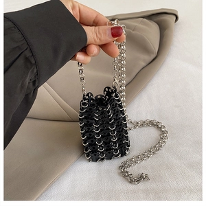 Detail of handmade woven mini bag with black sequins, metal rings and silver chain strap