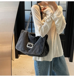 Macro detail of dark grey denim tote bag showing metal buckle and chain shoulder strap