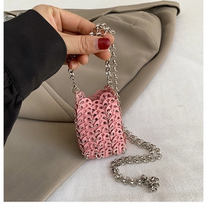 Detail of pink metal sequin woven mini bag with silver chain strap held by hand