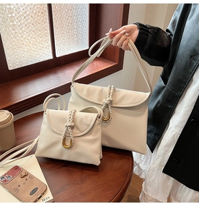 Detail of cream leather shoulder bags with hand-woven strap and golden U-shaped buckle